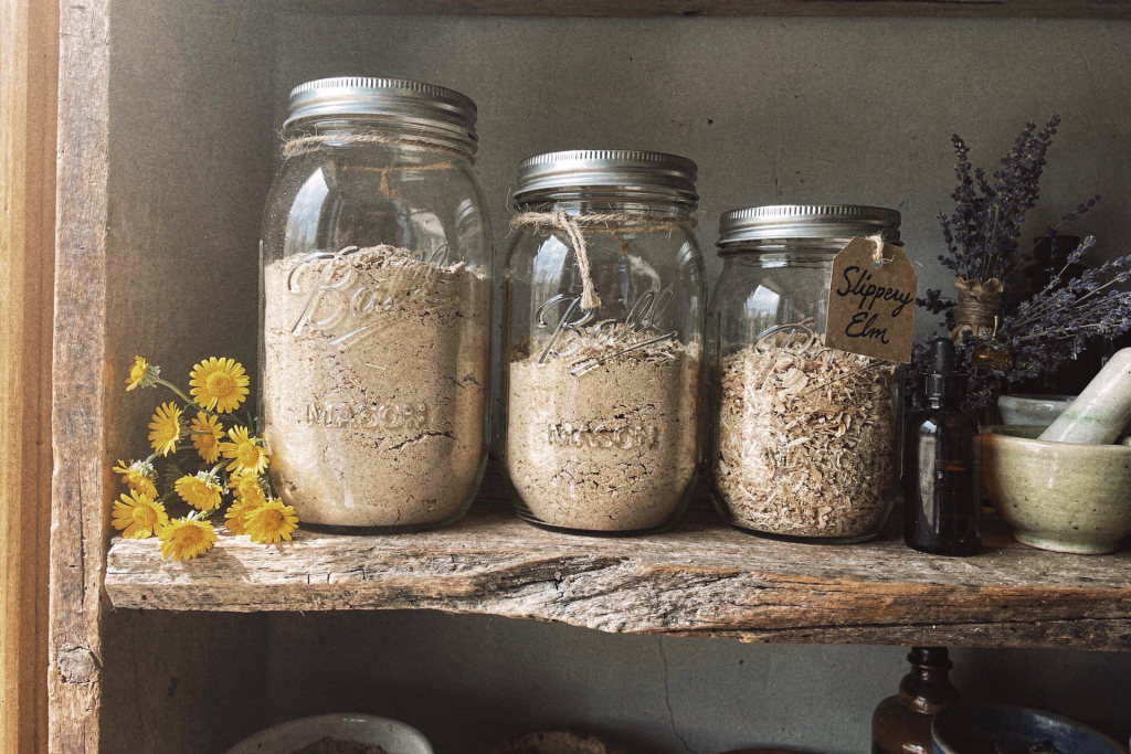 Mason jars of slippery elm powder on a rustic wooden apothecary shelf
