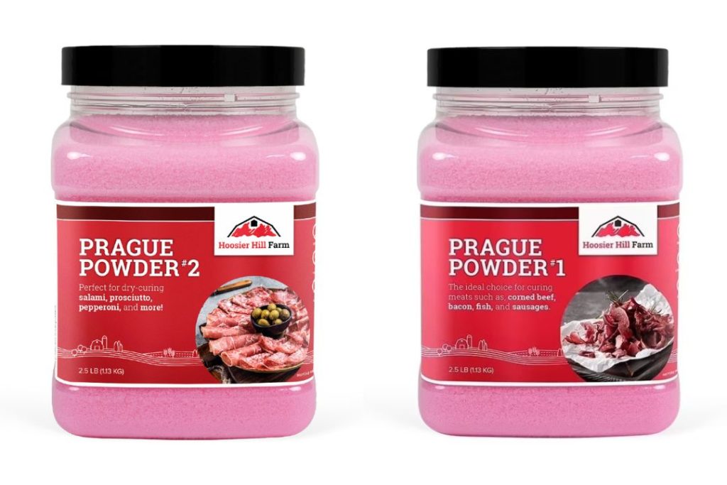 Two small glass bowls side by side holding pink Prague Powder #1 and Prague Powder #2, the modern food-safe alternatives to traditional saltpeter for home meat curing.