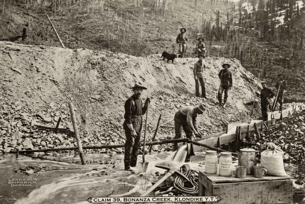 Sepia Gold Rush archive photograph of Klondike prospectors working a placer mining claim, with jars of sourdough starter among their camp supplies.